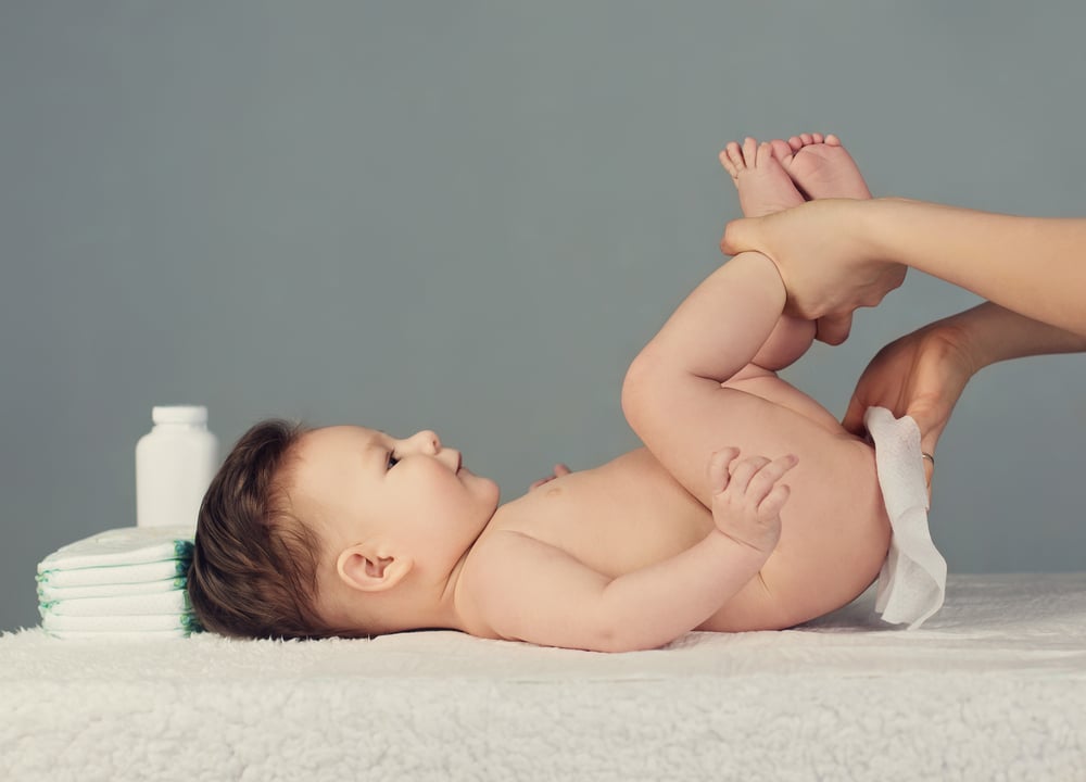 Une femme soulage l'érythème fessier du bébé en le massant.