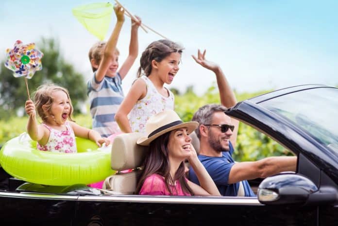 Une famille profite des vacances en conduisant dans une voiture décapotable.