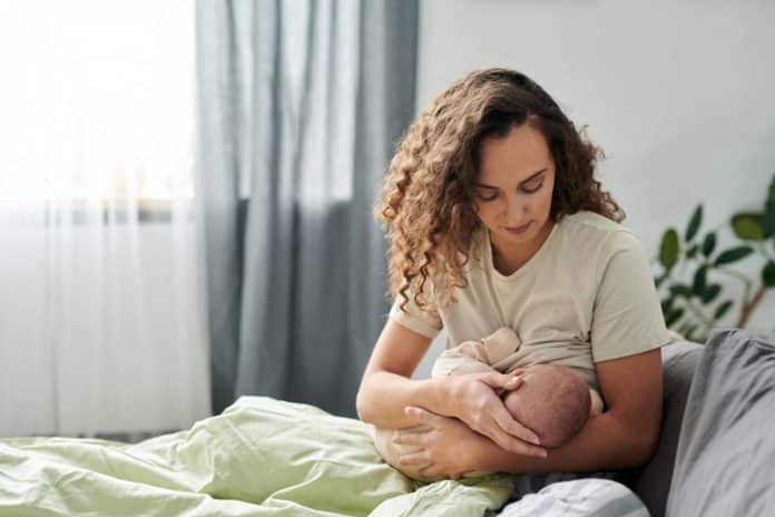 Une femme allaite son bébé calmement dans le lit.
