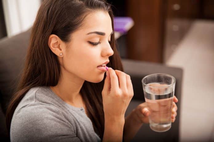 Une femme prend des vitamines dans un verre.
