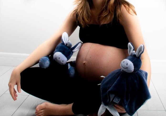 Femme enceinte assise avec deux doudou bébé lapin.
