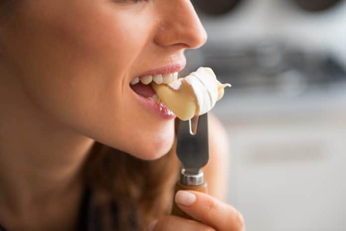 Gros plan d'une femme enceinte dégustant une bouchée de dessert crémeux sur une fourchette.