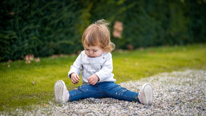 Un enfant en bas âge est assis sur le sol en plein air, les jambes tendues, concentré sur le jeu avec des petits cailloux ou du gravier - parfait pour les parents soucieux de la gestion taille enfants lorsqu'ils choisissent des vêtements pour enfants pour le jeu actif. Un enfant en bas âge est assis sur le sol en plein air, les jambes tendues, concentré sur le jeu avec des petits cailloux ou du gravier - parfait pour les parents soucieux de la gestion taille enfants lorsqu'ils choisissent des vêtements pour enfants pour le jeu actif.