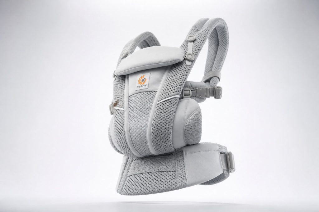 Porte-bébé physiologique gris clair avec bretelles rembourrées et tissu en maille, présenté sur un fond blanc uni ; fait partie de notre sélection 2026 pour le meilleur porte-bébé.